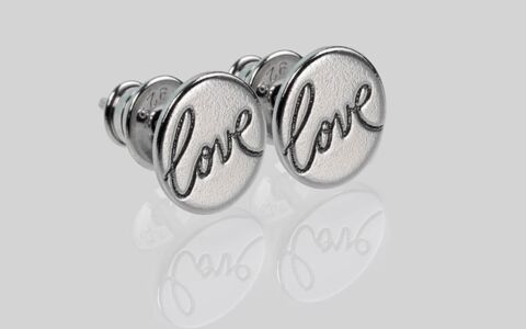 Makroaufnahme von schöne Ohrstecker aus Silber mit Gravur Love und Spiegelung